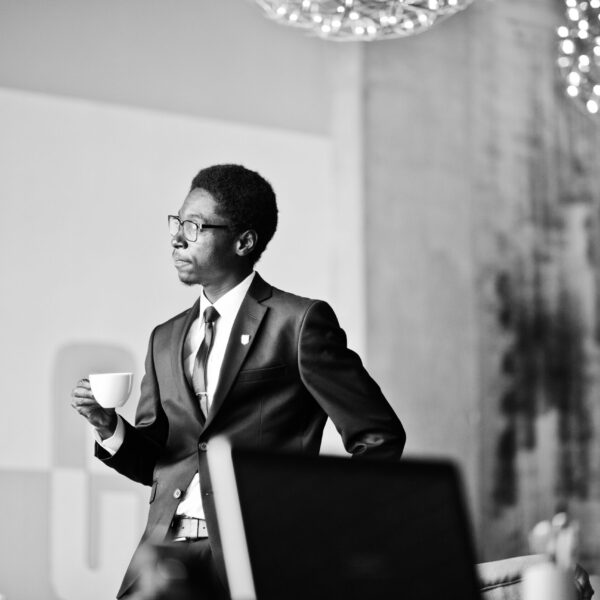 Business african american man wear on black suit and glasses at office, drinking morning coffee before work day.
